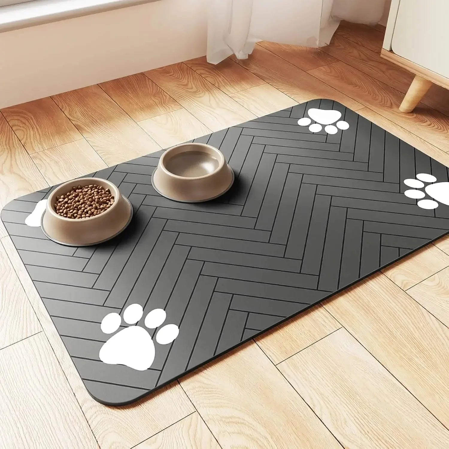Grey waterproof pet feeding mat with paw print design and food and water bowls on a wood floor