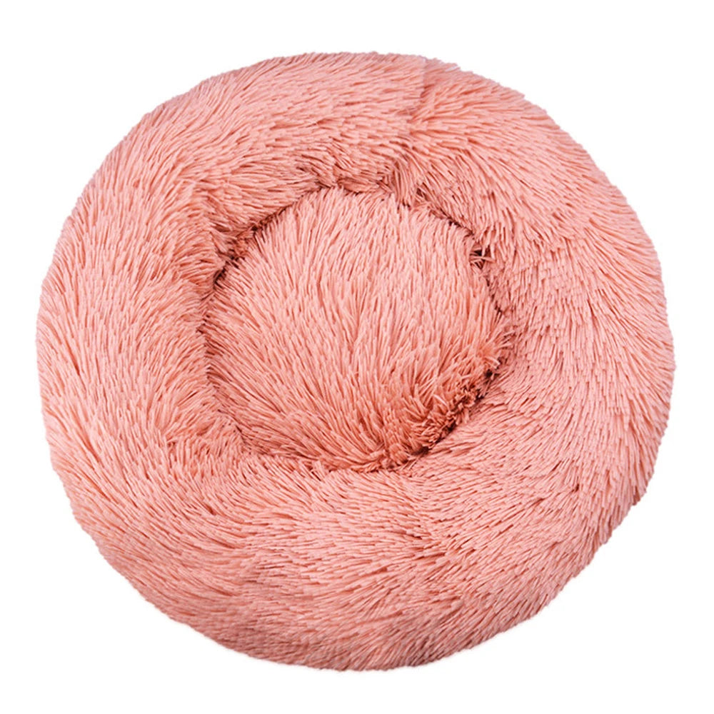 Top-down view of a round plush calming dog bed in coral pink faux fur