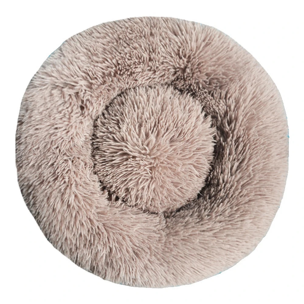 Top-down view of a round plush calming dog bed in blush pink faux fur