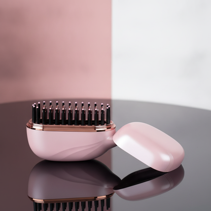 Pink and rose gold hairbrush on a reflective surface with a gradient background